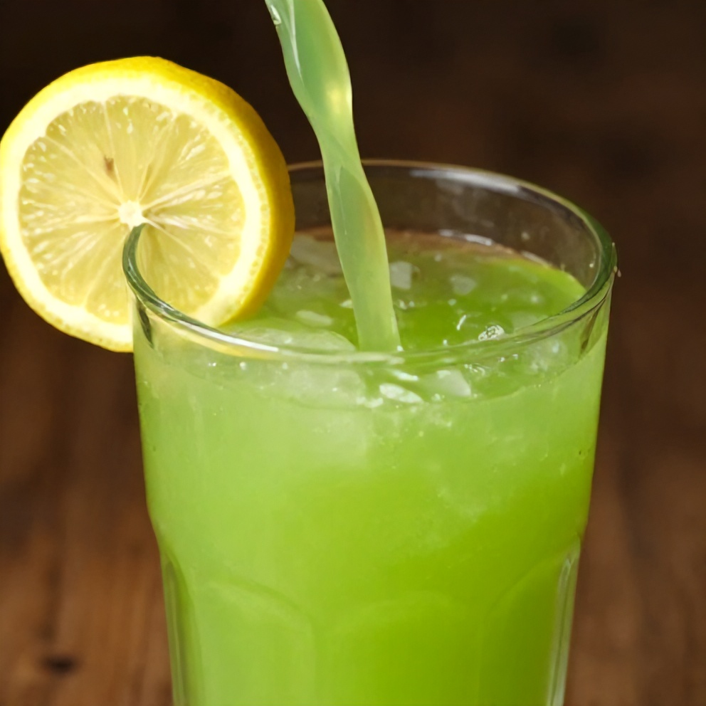 Poured glass of green celery apple juice with a lemon slice